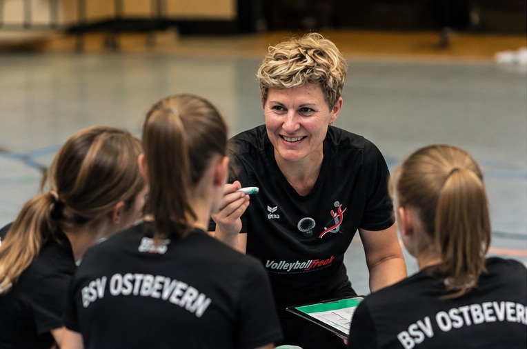 Lisa Thomsen im Gespräch mit Volleyballspielerinnen an der Seitenlinie